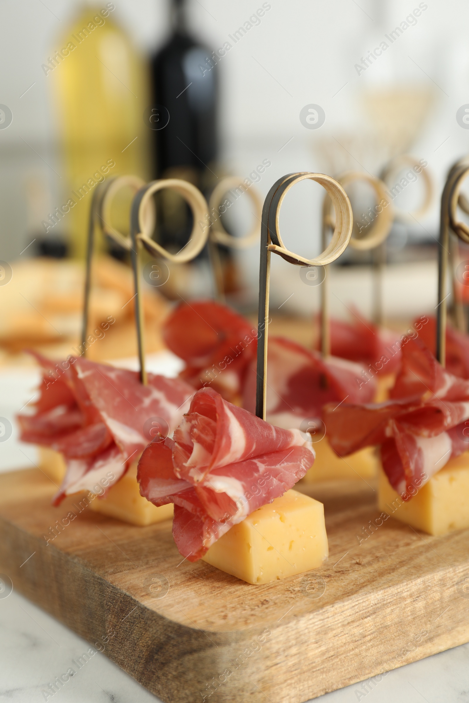 Photo of Tasty canapes with cheese and ham on white marble table, closeup