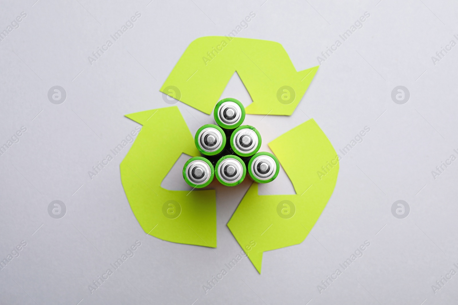 Photo of Used batteries and recycling symbol on white background, top view