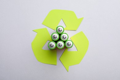 Photo of Used batteries and recycling symbol on white background, top view