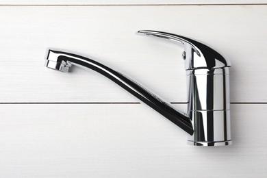 Photo of Single handle water tap on white wooden table, top view