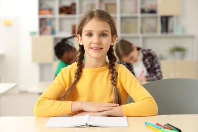 Portrait of smiling little girl studying in classroom at school