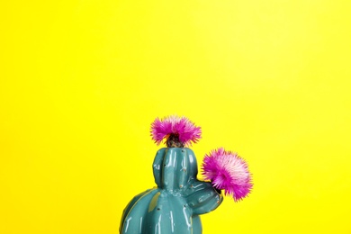 Photo of Trendy cactus shaped ceramic vase with flowers on color background