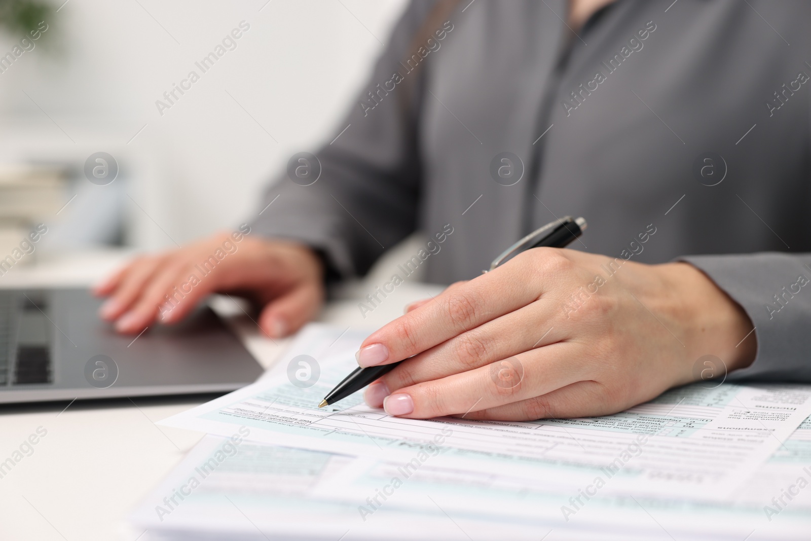 Photo of Secretary doing paperwork at table in office, closeup