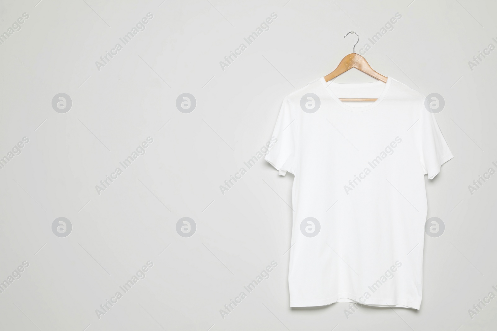 Photo of Hanger with blank t-shirt on white background. Mock up for design