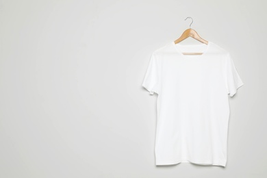 Photo of Hanger with blank t-shirt on white background. Mock up for design