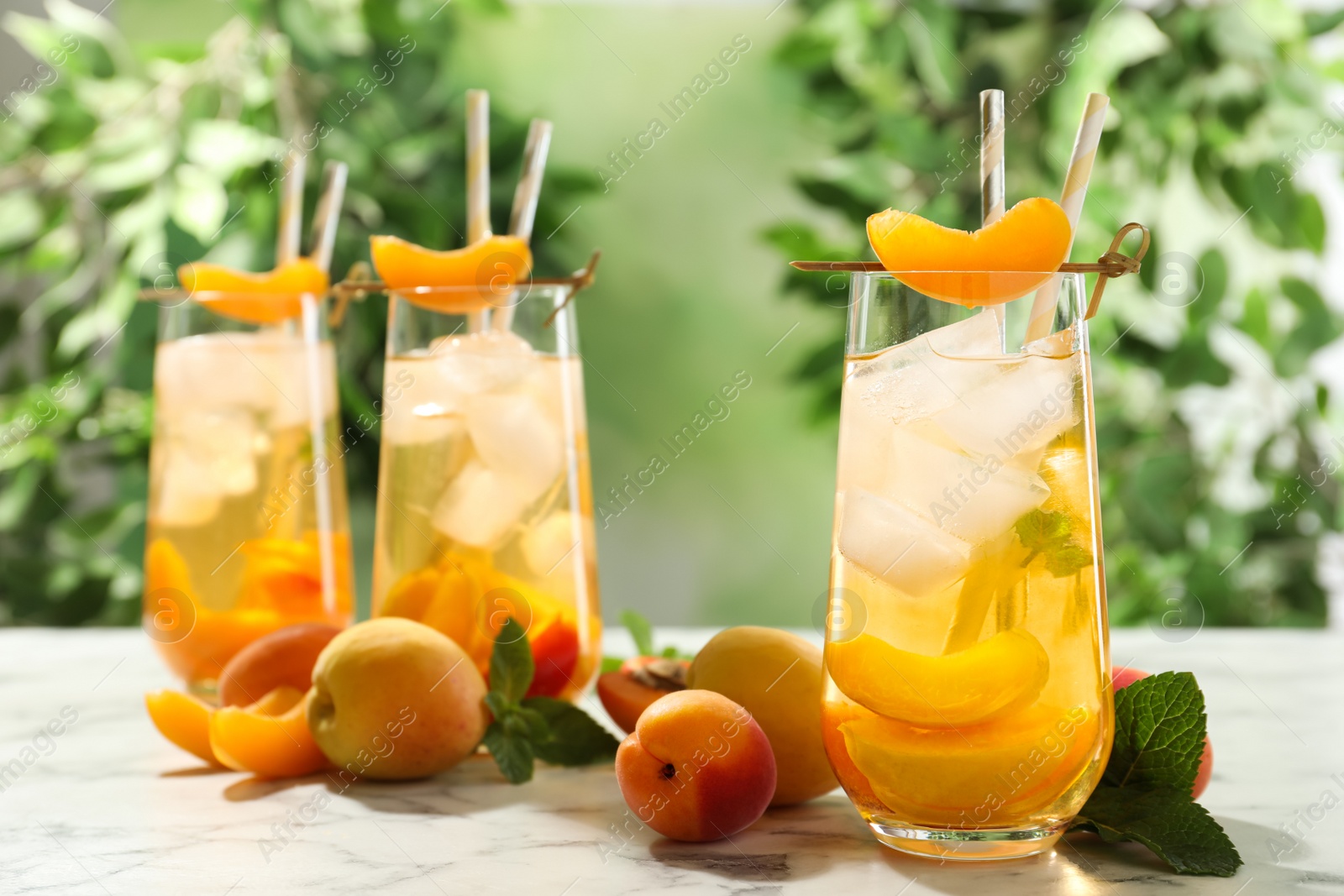 Photo of Delicious refreshing drink with apricot on white marble table