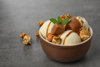 Photo of Delicious ice cream with caramel and popcorn in dessert bowl on table. Space for text