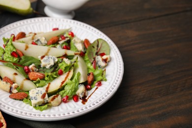 Delicious pear salad with sauce on wooden table, closeup. Space for text