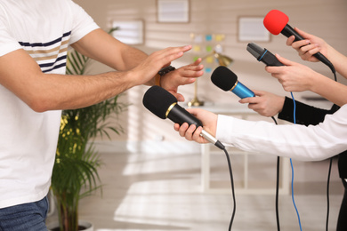 Photo of Man avoiding journalist's questions at interview indoors, closeup view