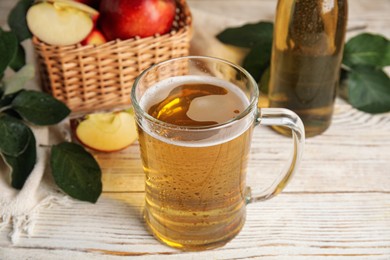Photo of Delicious apple cider in glass mug on white wooden table