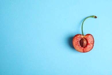 Photo of Cut sweet cherry on light blue background, top view. Space for text