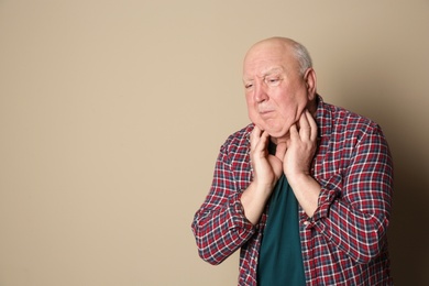 Photo of Senior man suffering from cough on color background. Space for text