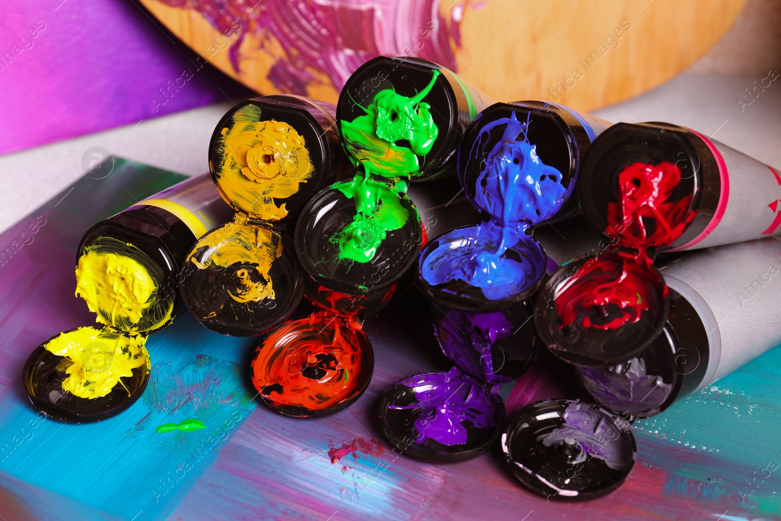 Photo of Tubes of colorful paints and canvas on table, closeup