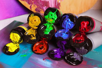 Tubes of colorful paints and canvas on table, closeup