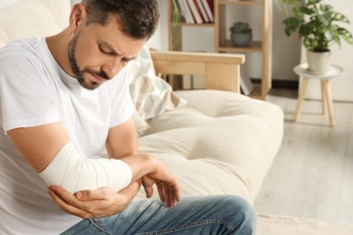 Photo of Man with arm wrapped in medical bandage at home