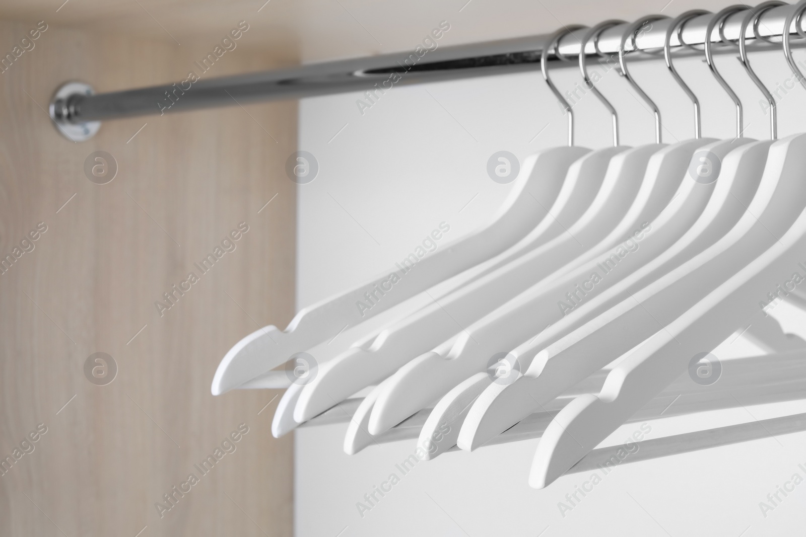 Photo of Clothes hangers on metal rail in wardrobe