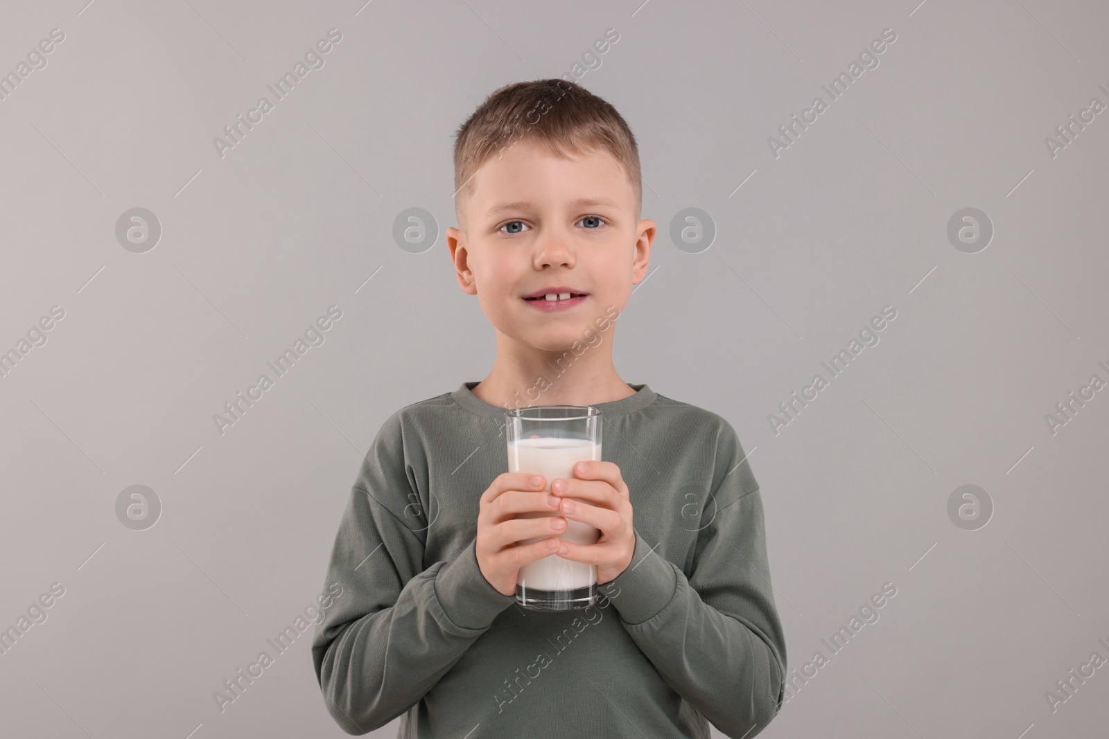 Photo of Cute boy with glass of fresh milk on light grey background