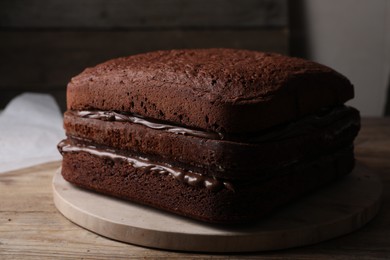 Delicious homemade layer cake with chocolate cream on wooden table, closeup