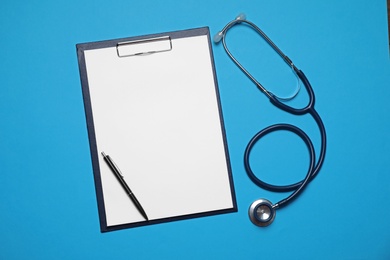 Photo of Clipboard, stethoscope and pen on light blue background, flat lay