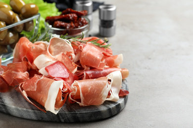 Pile of tasty prosciutto on light grey table, closeup