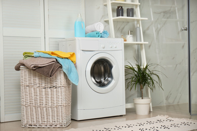 Wicker basket with laundry and washing machine in bathroom