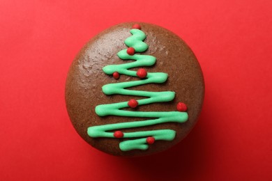 Photo of Beautifully decorated Christmas macaron on red background, top view