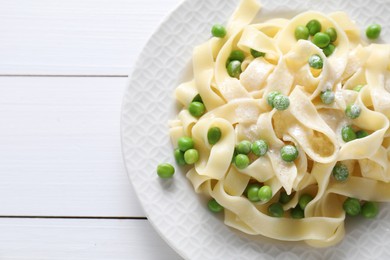 Photo of Delicious pasta with green peas on white wooden table, top view. Space for text