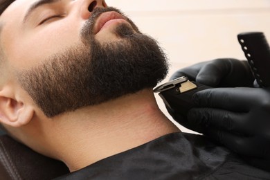 Professional hairdresser working with client in barbershop, closeup