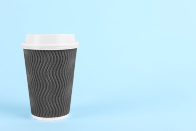 Brown paper cup with plastic lid on light blue background, space for text. Coffee to go