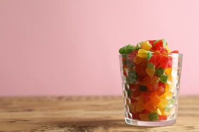 Photo of Delicious candies in glass on wooden table, closeup. Space for text