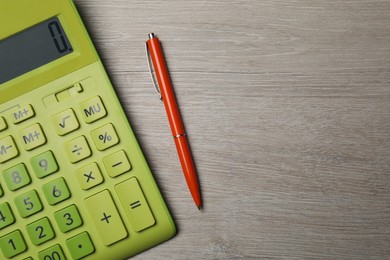 Photo of Calculator and pen on wooden table, top view. Space for text