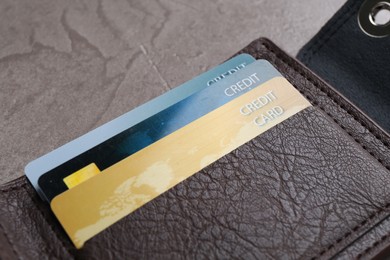 Photo of Credit cards in leather wallet on grey table, closeup