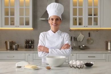 Portrait of professional chef near table with ingredients in kitchen