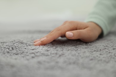 Photo of Woman touching soft grey carpet, closeup view