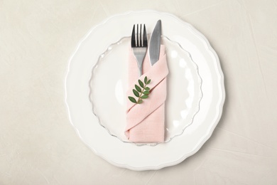 Plate, cutlery and napkin on light background, top view