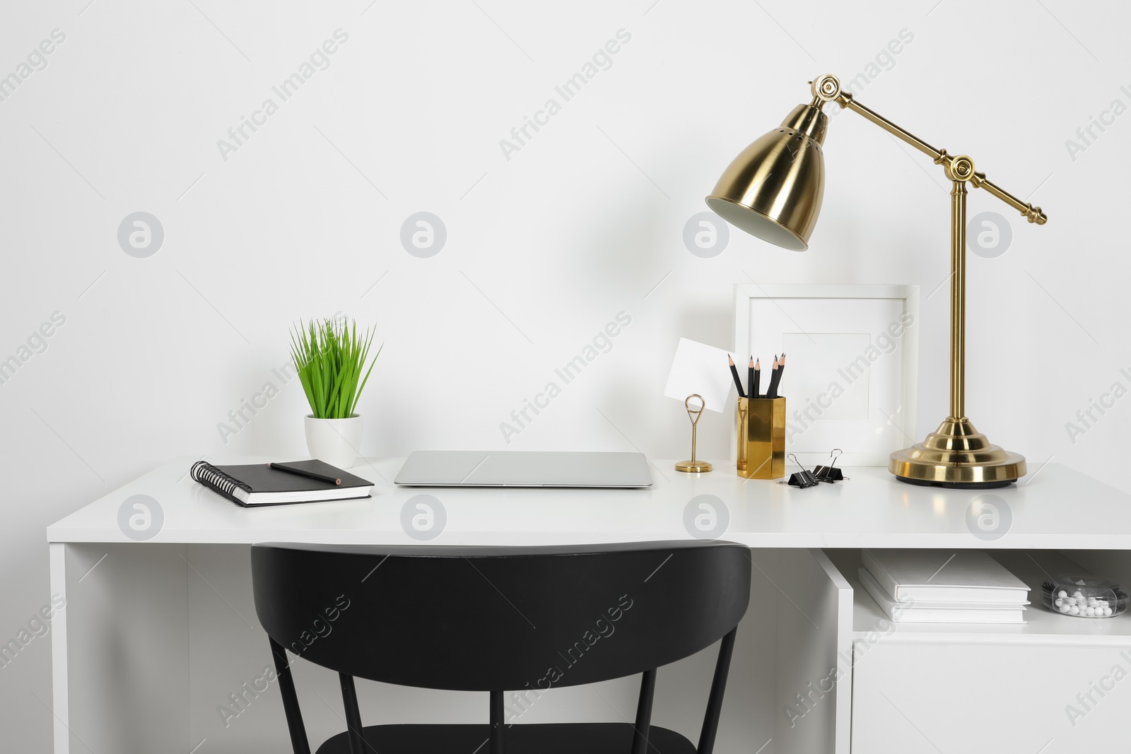 Photo of Cozy workspace with laptop, lamp and stationery on wooden desk at home