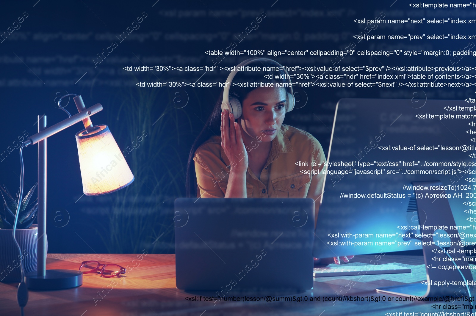 Image of Programmer with headphones working in office at night