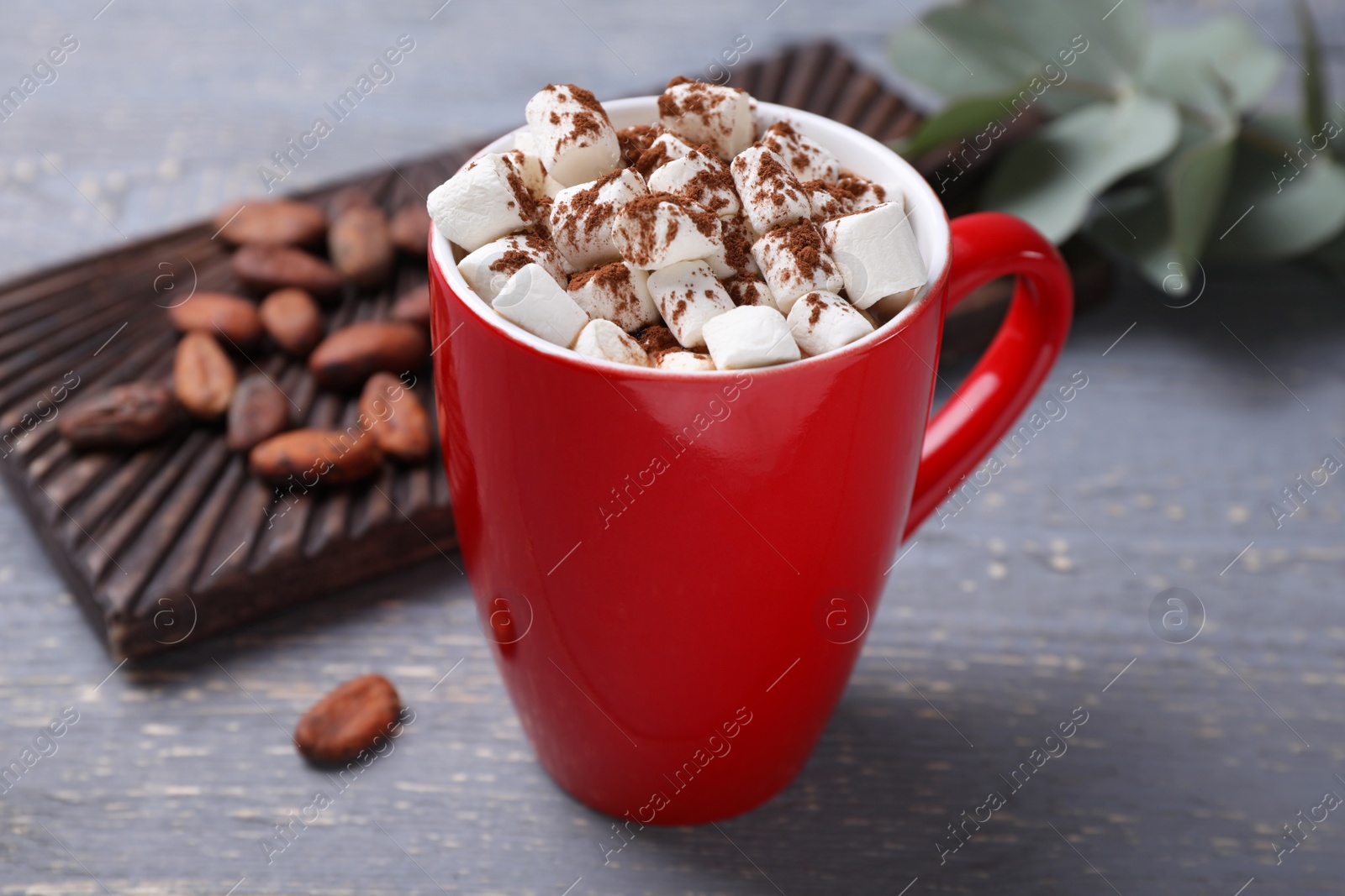 Photo of Cup of tasty cocoa with marshmallows and beans on grey wooden table