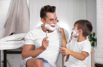 Photo of Father and son having fun while shaving in bathroom