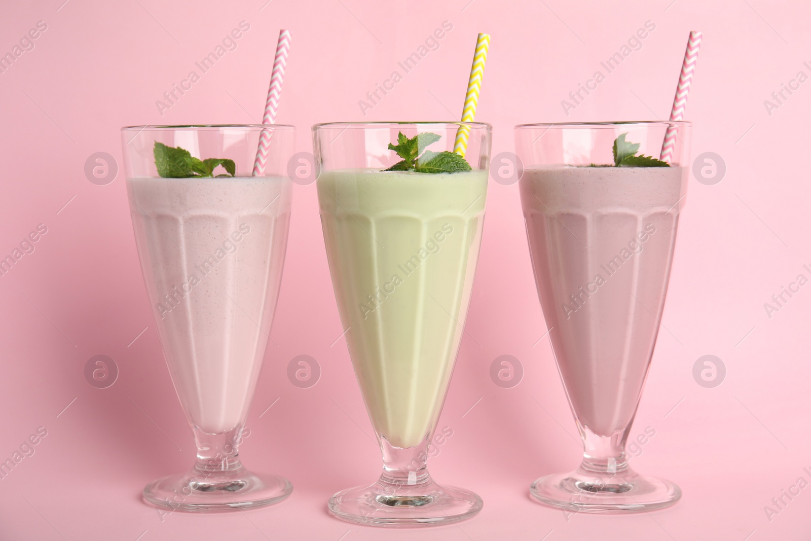 Photo of Tasty fresh milk shakes on pink background