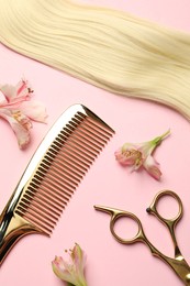 Photo of Hairdresser tools. Blonde hair lock, comb, scissors and flowers on pink background, flat lay