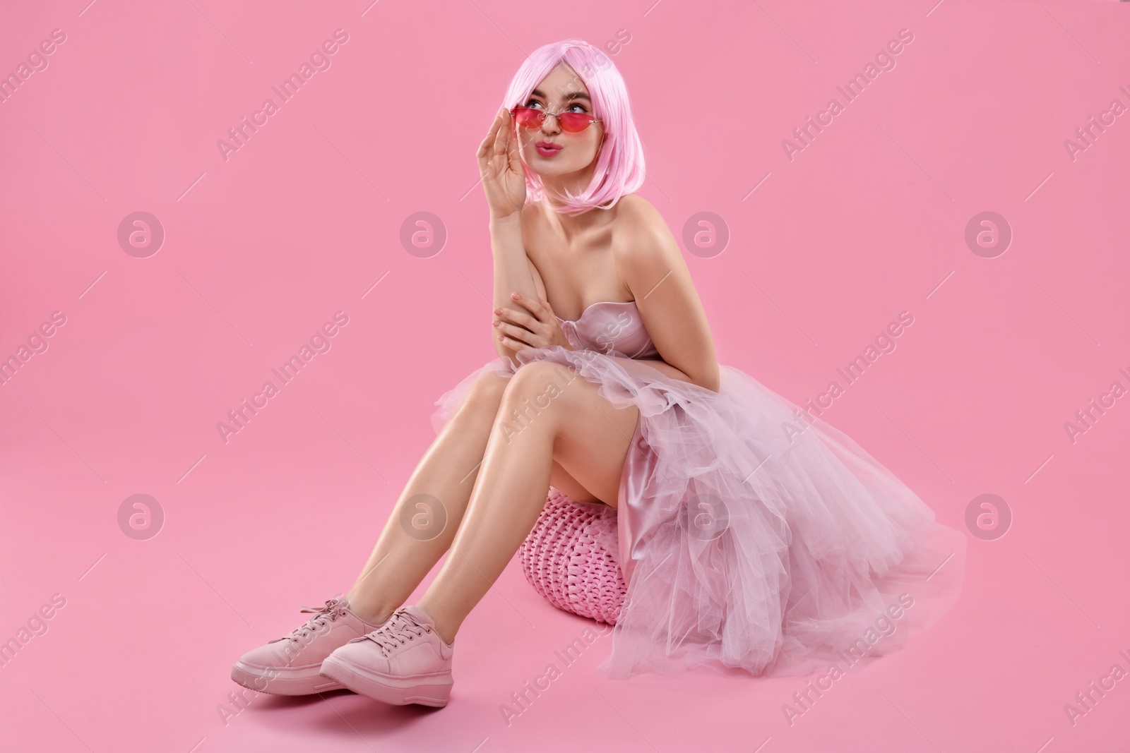 Photo of Pink look. Beautiful woman in dress and wig on color background