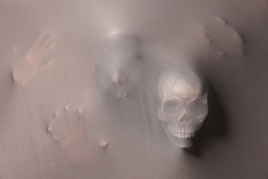Photo of Silhouette of creepy ghost with skulls behind grey cloth