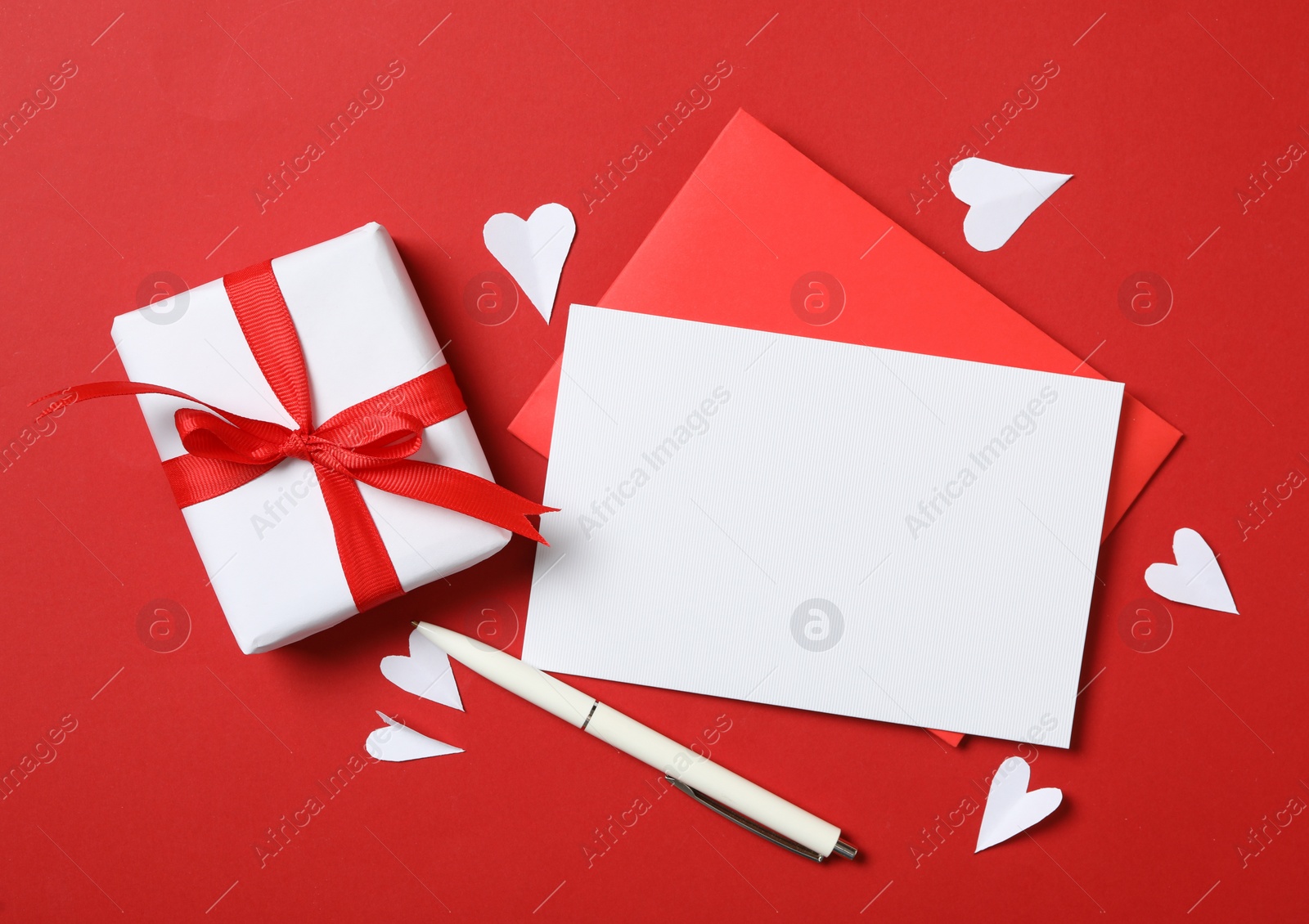 Photo of Flat lay composition with blank card on red background, space for text. Valentine's Day celebration