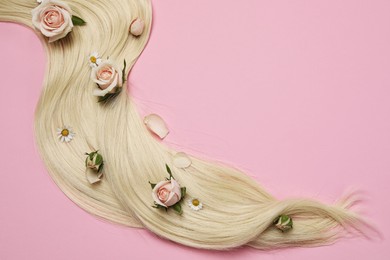 Photo of Lock of healthy blond hair with flowers on pink background, flat lay. Space for text