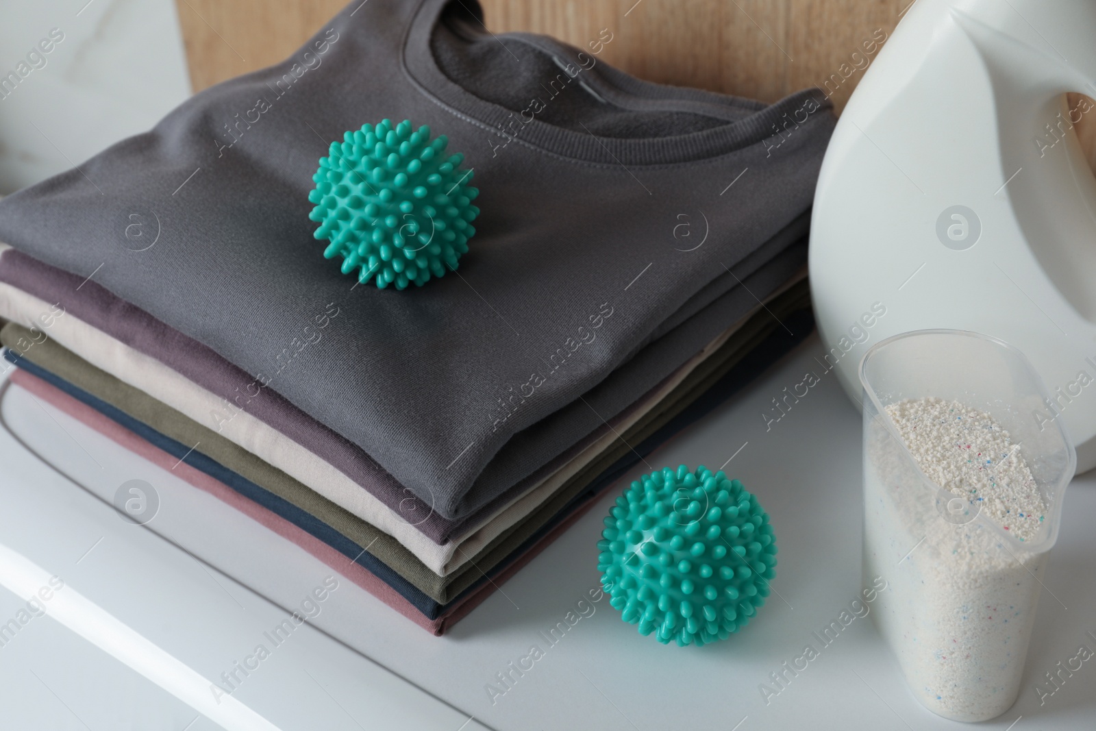 Photo of Dryer balls, stacked clean clothes and detergents on washing machine