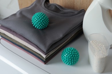 Dryer balls, stacked clean clothes and detergents on washing machine