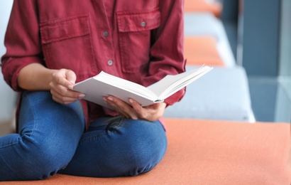 Young woman reading book in library, closeup