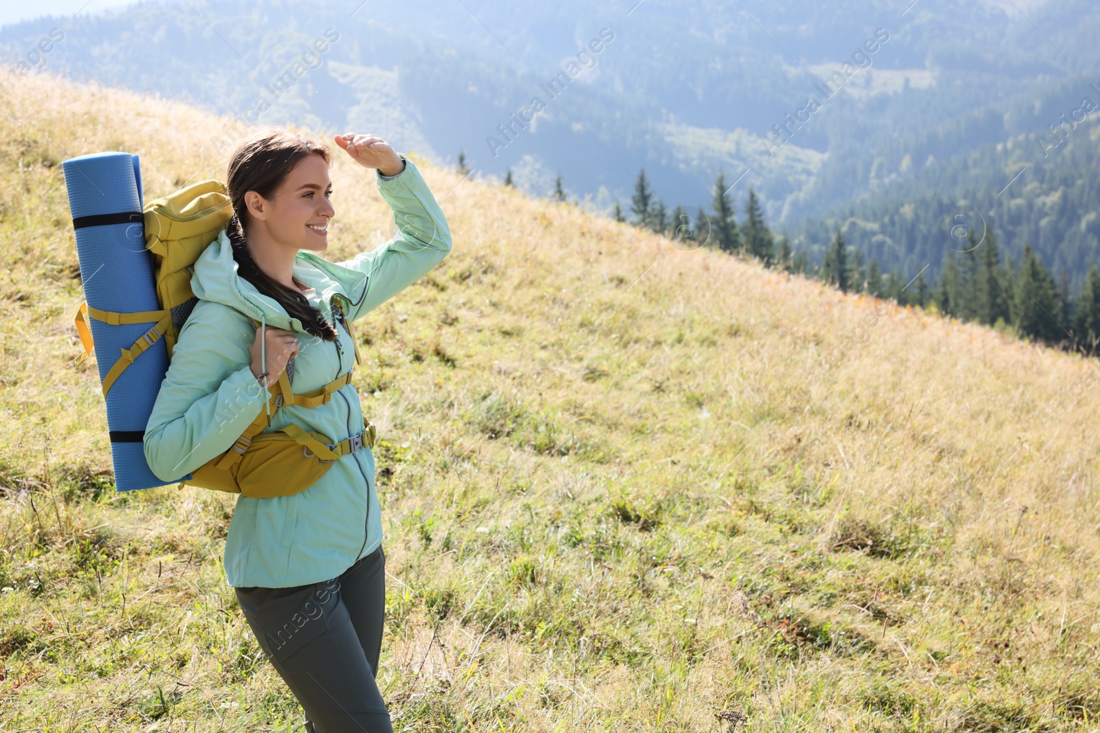 Photo of Tourist with backpack and sleeping pad in mountains on sunny day