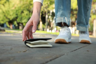 Woman picking up white leather purse outdoors, closeup. Lost and found